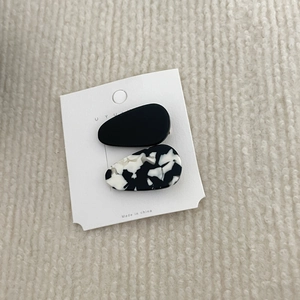 Close-up of teardrop acetate hair clips in black and marble pattern on plush background