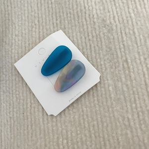 Close-up of two acetate waterdrop hair clips in navy blue and marble pattern on a card
