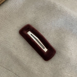 Eleganter rechteckiger Samt-Haarclip in Burgunderrot auf weichem Strickhintergrund