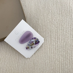 Detail of teardrop hair clips in matte purple and marble pattern on white card display