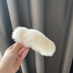 Close-up of a large white plush faux rabbit fur claw clip with a fluffy texture