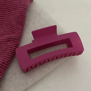 Elegante magenta matte haarklem voor dik haar gepresenteerd op een zachte stof
