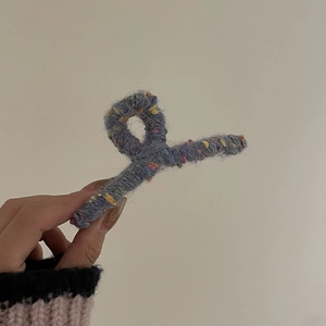Pince à cheveux en tricot bleu avec pois colorés tenue en main pour un style cozy