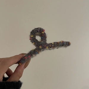 Gros plan d'une pince à cheveux en tricot gris avec texture de tissu arc-en-ciel