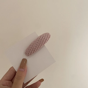 Gros plan sur la pince à cheveux ovale en tricot rose montrant la texture de la laine