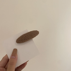 Détail d'une pince à cheveux ovale en tricot marron avec texture laineuse pour femmes en hiver