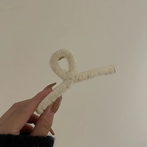 Détail d'une pince à cheveux en laine crème avec de subtiles paillettes brillantes