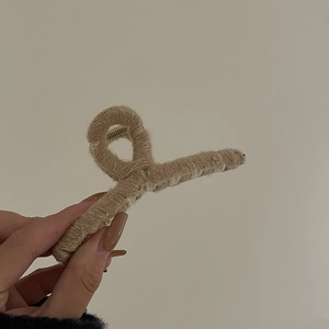 Détail de la maille beige douce et des griffes en métal de cette pince à cheveux hiver