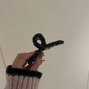 Détail d'une pince à cheveux noire en maille avec mécanisme à ressort métallique