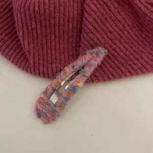 Détail d'une pince à cheveux en laine arc-en-ciel faite main avec une texture rose duveteuse