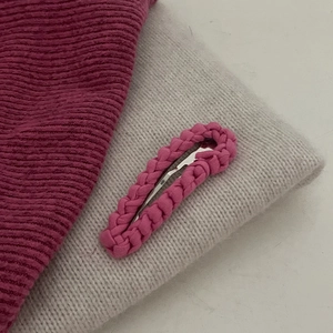 Detail van roze tweed haarklem met dikke gevlochten textuur en een metalen basisclip