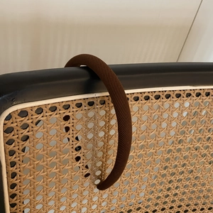 Serre-tête en éponge marron avec texture en sergé sur un dossier de chaise en rotin