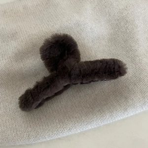 Pinza per capelli in finta pelliccia marrone scuro su maglia beige per l'inverno