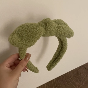 Détail d'un bandeau en peluche vert avocat avec polaire douce et un joli nœud décoratif