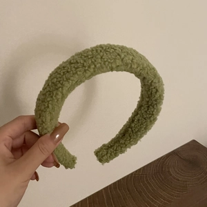 Détail d'un serre-tête en peluche vert moutarde avec une texture épaisse en laine
