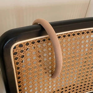 Détail du serre-tête rembourré beige avec texture sergé sur une chaise en rotin noir