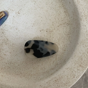 Close-up of tortoise shell acetate hair clip in cream and black on ceramic plate