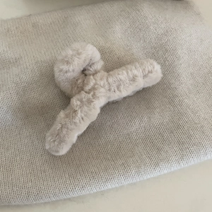 Dettaglio della morbida texture in finta pelliccia beige di questa grande pinza per capelli