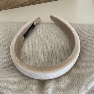 Close-up of velvet padded headband in champagne beige with handmade label on knit fabric