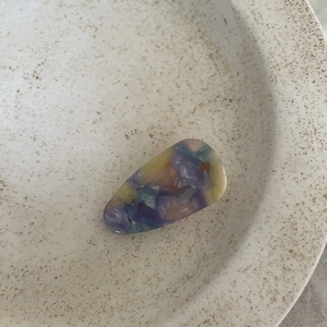 Detail of French acetate hair clip with colorful marble texture on a ceramic plate