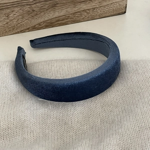 Close-up of deep blue velvet headband with textured fabric and internal brand label