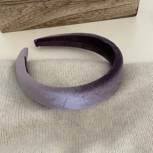 Detailed texture of lavender velvet padded headband placed on beige knit fabric