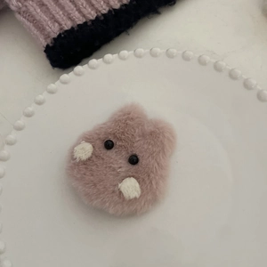 Détail d'une pince à cheveux lapin en peluche rose avec texture douce sur une assiette