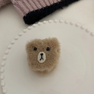 Détail d'une pince à cheveux ours en peluche marron avec texture douce sur plat blanc