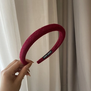 Detail view of burgundy velvet headband featuring a Hand Made label on inner side