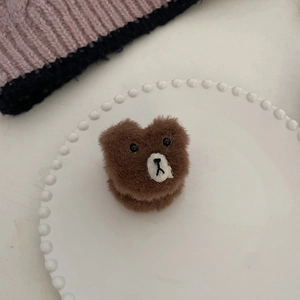 Détail d'une pince à cheveux en peluche ours brun doux sur une assiette en céramique