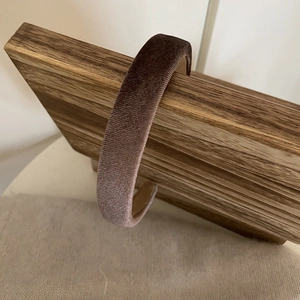 Detailed view of deep brown velvet padded headband on a wooden display stand