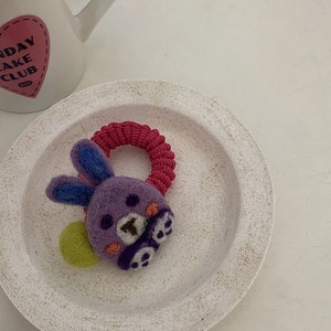 Detail of handmade purple wool felt rabbit hair tie with pink elastic band and green pompom