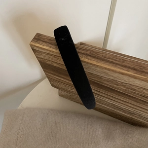 Detailed view of the wide black velvet headband on a natural wooden display stand