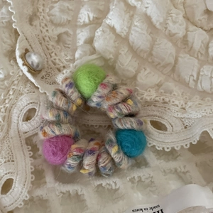 Dettaglio di elastico per capelli in feltro di lana con texture colorata su pizzo