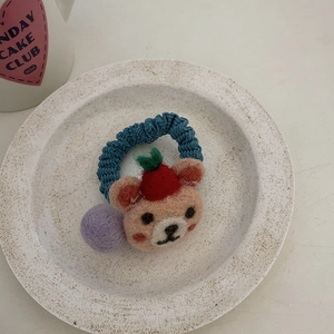 Detail view of handmade wool felt bear hair tie with blue knit band and purple felt ball