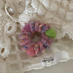 Dettaglio di un elastico per capelli a spirale intrecciato con palline di feltro