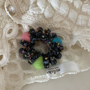 Dettaglio dell'elastico per capelli in tweed con palline di feltro colorate su pizzo