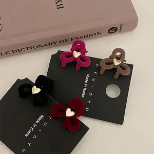 Pinzas para el pelo con lazo de terciopelo y corazón dorado en varios colores sobre libro
