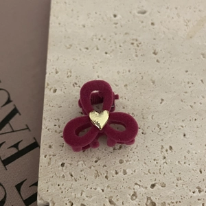 Primer plano de pinza para el pelo aterciopelada magenta con detalle de corazón dorado