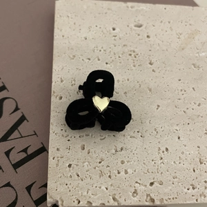 Mini pinza de pelo de terciopelo francés con corazón dorado sobre fondo de piedra