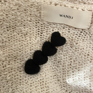 Cute black plush heart hair clip with four connected 3D hearts on knit background