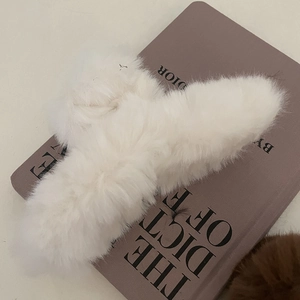 Détail d'une grande pince à cheveux en fausse fourrure blanche sur un livre violet