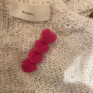 Pink plush heart hair clip for women with soft faux fur texture on knit background