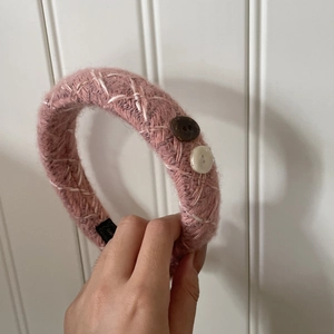 Détail du bandeau en maille rose avec texture, coutures blanches et des boutons