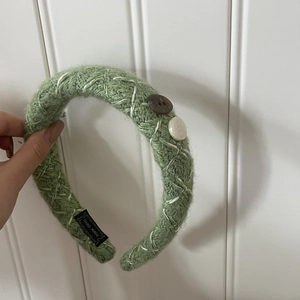 Détail du bandeau en maille verte avec coutures blanches, boutons et étiquette faite main