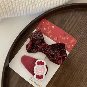 Dettaglio di fermagli natalizi con fiocco di velluto rosso e ricamo a forma di caramella