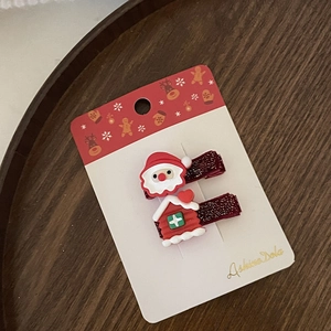 Dettaglio di fermagli natalizi con Babbo Natale e casetta su cartoncino rosso