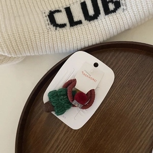 Dettaglio dell'elastico per capelli ad albero di Natale fatto a mano con pompon rosso