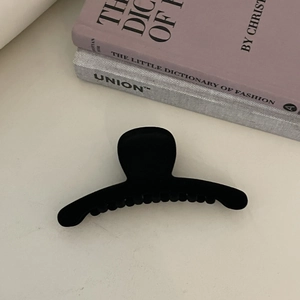 Large black flocked geometric hair claw clip for women on a white minimalist background