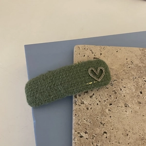 Detail of tweed BB clip hair accessory with sparkling rhinestone heart on a green base